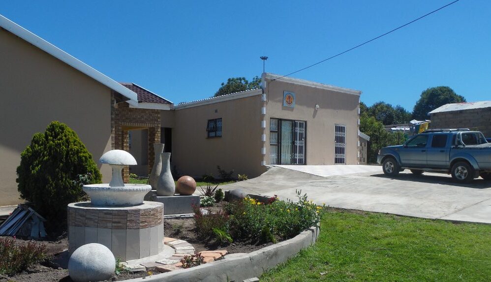 Ellenicha Guest House front garden with a fountain, driveway and reception building